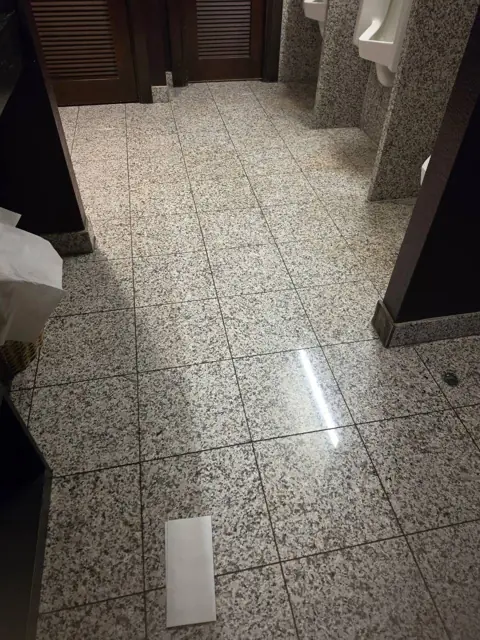 Restroom floor in an Indianapolis commercial facility before cleaning: litter and dull spots on the tile floor