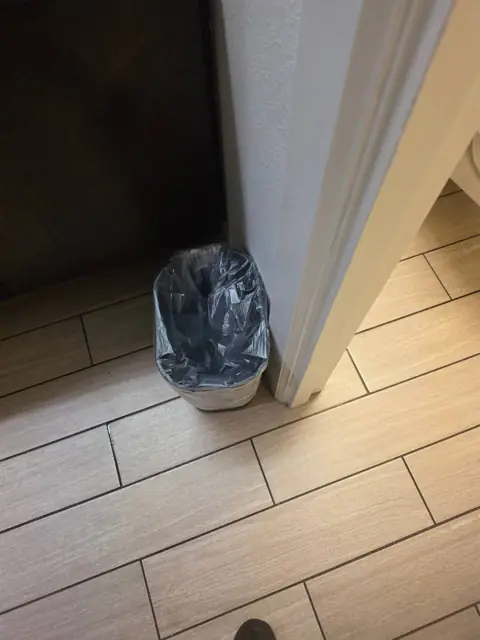 Restroom trash area in an Indianapolis commercial facility after cleaning: trash removed, can relined and floor cleaned